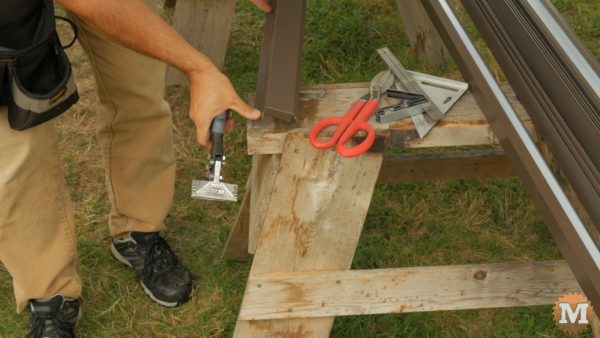 Using tin snips and hand seaming tool to bend tabs on rake trim
