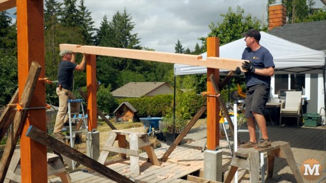 lifting a beam of the Three Gable Timber Frame style Pavilion into place