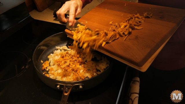 Adding chopped Winter Chanterelle Mushrooms to the onions in the frying pan.