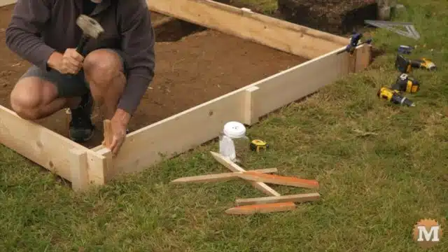 setting concrete forms in place and securing with stakes hammered into the ground
