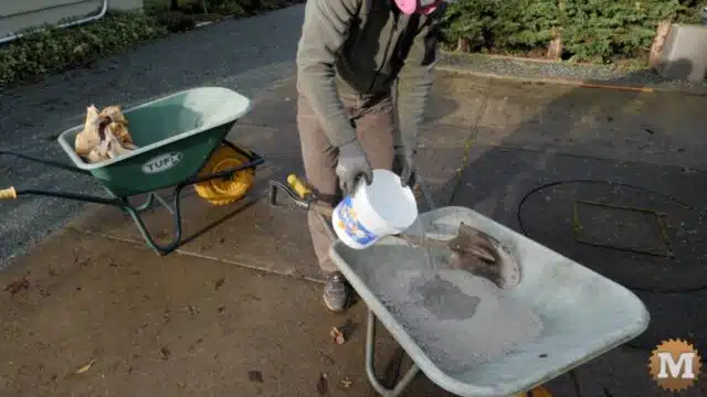 adding clean cold water to dry concrete mix in a wheelbarrow