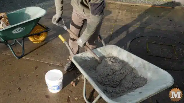 mixing concrete in a wheelbarrow with a shovel