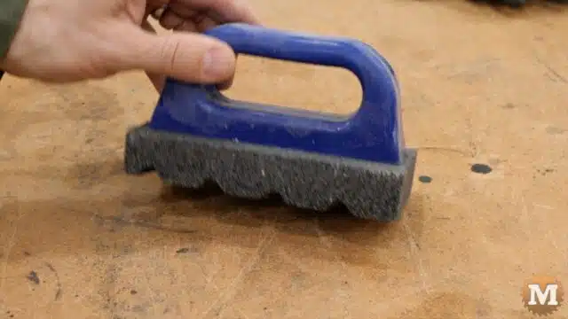a concrete rub brick tool with a blue plastic handle